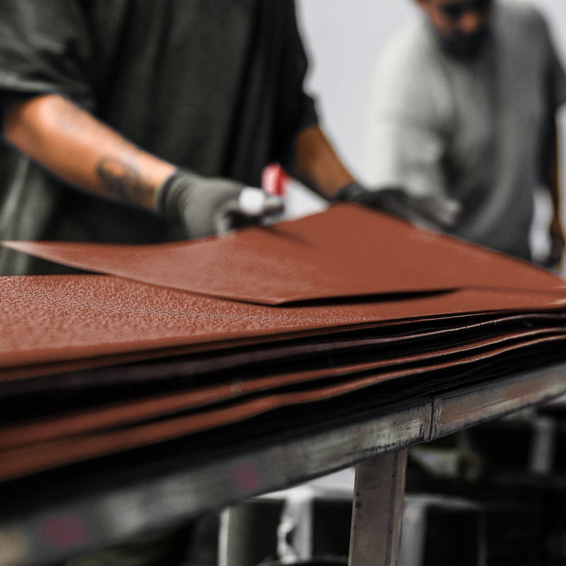 Worker cutting stacked brown abrasive material for narrow sanding belts