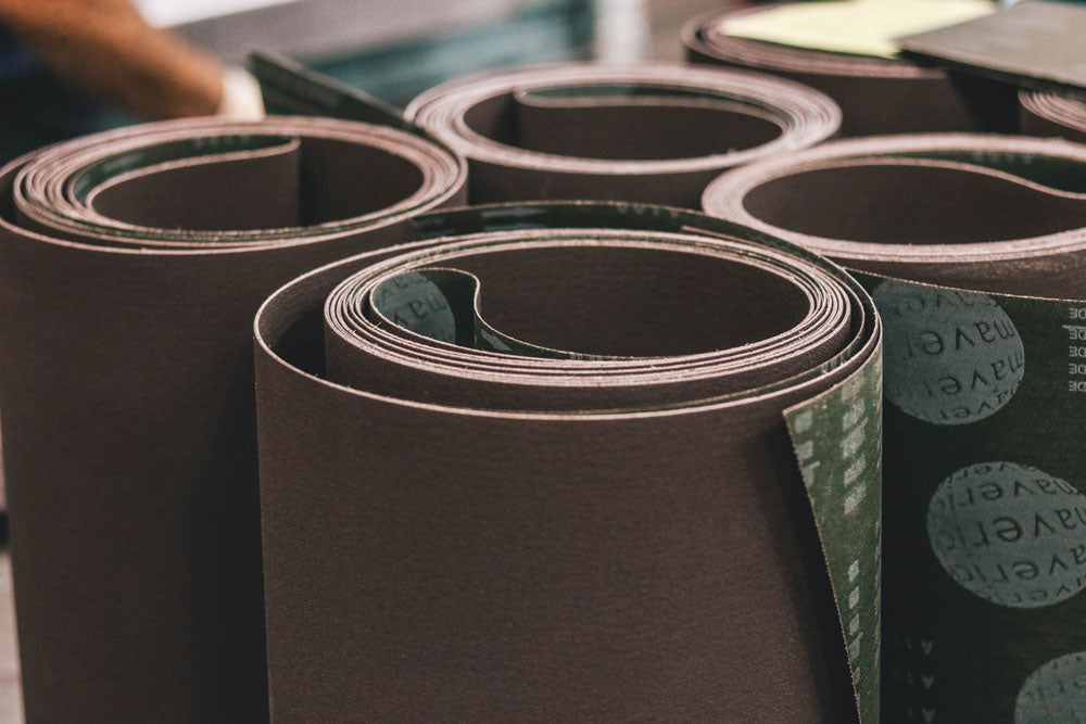 Coiled brown sanding belts arranged on a workshop table