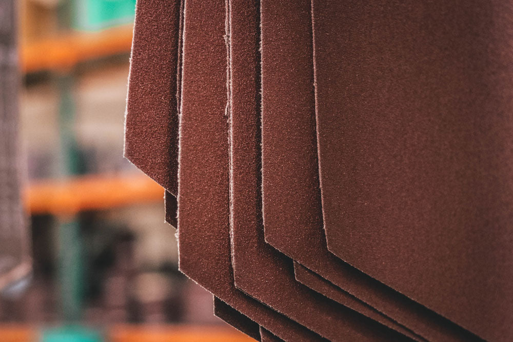 Close-up of layered brown abrasive belt strips hanging in a workshop
