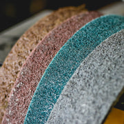 Pack of six 4x24-inch non-woven surface conditioning belts in brown, maroon, blue, and grey for various grit finishes.